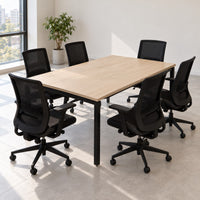 Mesa de reuniones rectangular para 6 personas con cubierta laminada color roble claro, patas metálicas negras tipo bench y seis sillas de malla en una sala de reuniones