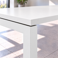 Detalle de la esquina de la mesa de reuniones para 8 personas: cubierta blanca de 25 mm con canto de PVC sobre estructura metálica blanca tipo bench de perfil 50 × 50 mm