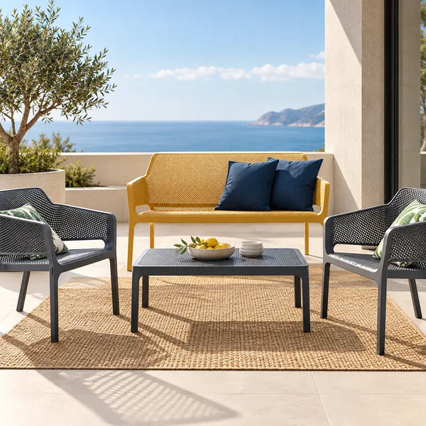 Banca de terraza amarilla y dos sillones gris oscuro con mesa de centro, en terraza con vista al mar – VICCA
