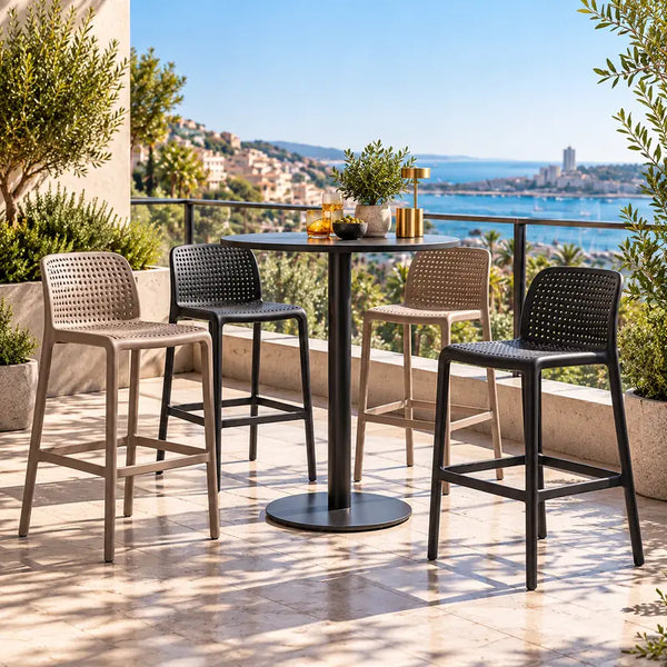 Taburetes altos de terraza en tortora y grafito junto a mesa alta redonda, en terraza con vista al mar – VICCA
